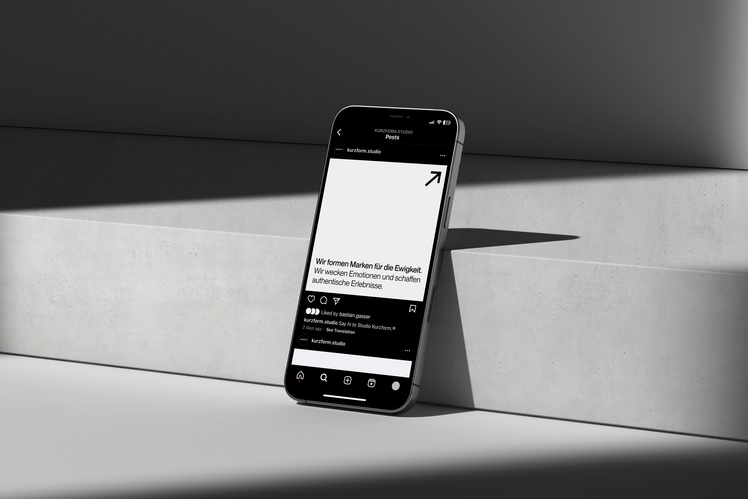 Smartphone mit ein Instagram Post von Kurzform geöffnet, angelehnt auf einer Betonstufe mit monochromer Umgebung