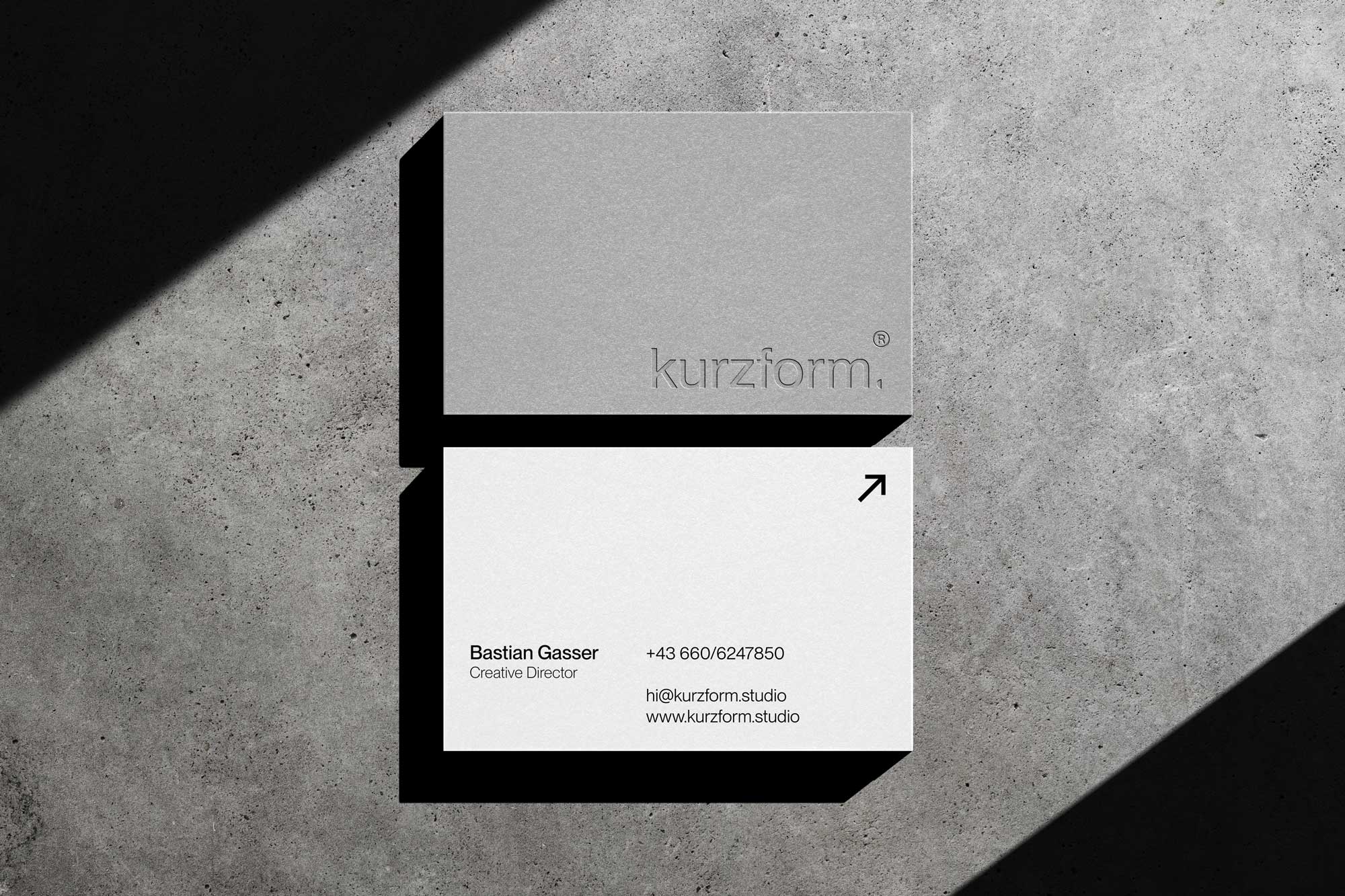 Visitenkarte kaschiert mit grauen und weißem Papier mit einer Kurzform Logo Prägung auf der grauen Seite. Rückseite zeigt Kontaktinformationen an.