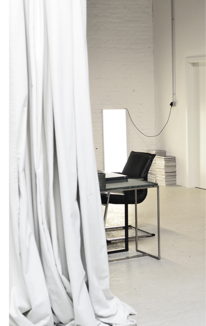 Minimalistisch gestaltetes Studio mit hellgrauen Gussboden und einem Vorhang